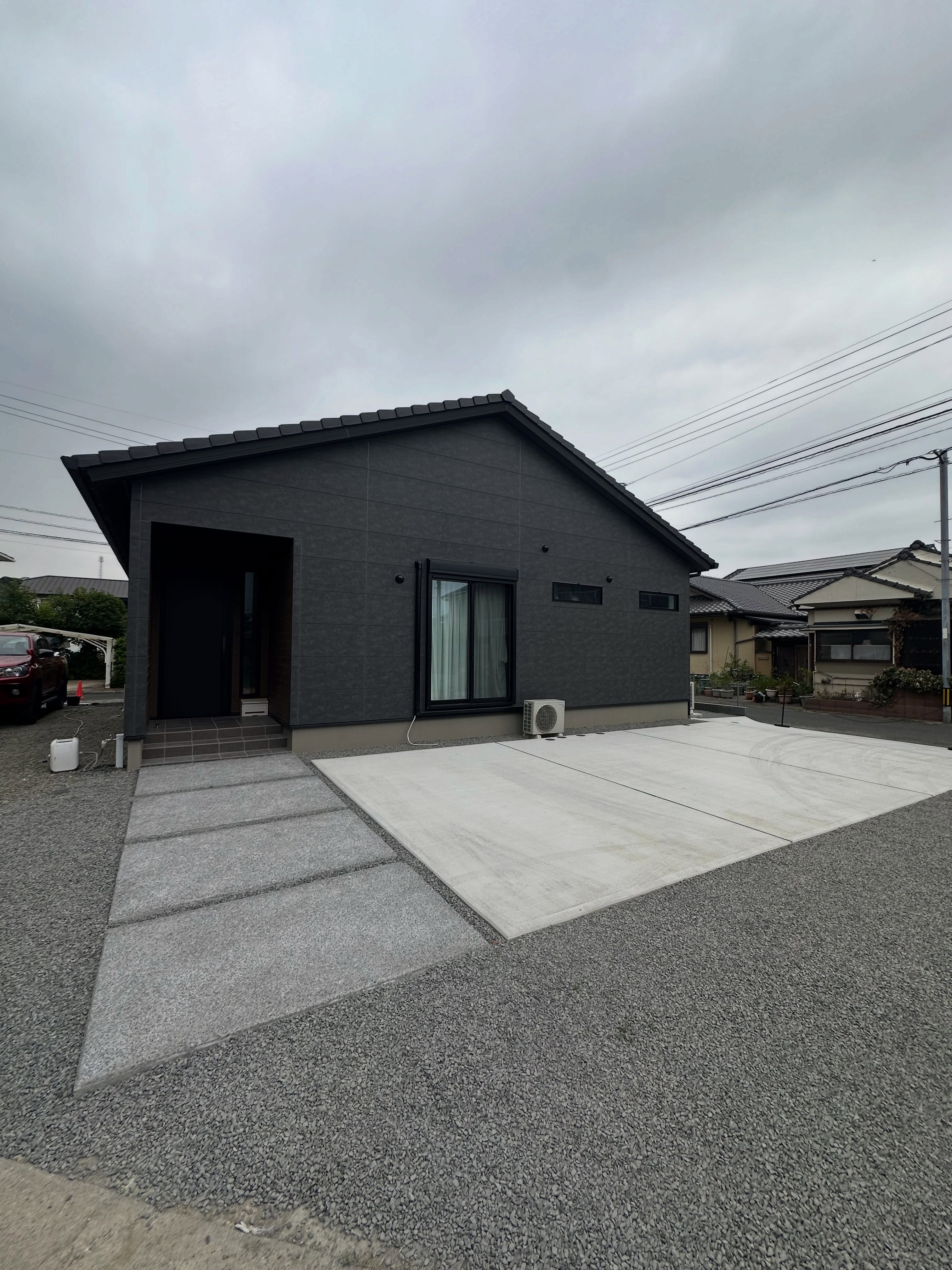 コンクリートの駐車場と玄関アプローチ、砂利を整えた施工後の敷地